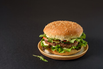 Vegetarian burger with bean patty and vegetables on black background