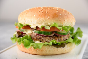 Vegetarian burger with bean patty on grey concrete background close up