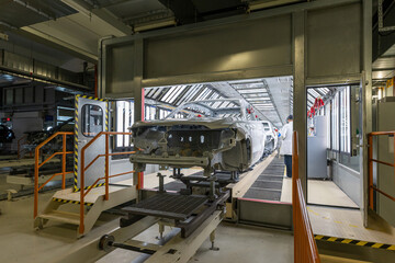 Naklejka premium Car body is on assembly line. Factory for production of cars. Modern automotive industry. Auto plant concept