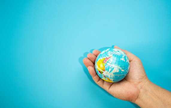 Hand hold the world map mockup over the blue background