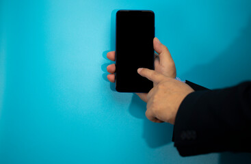 Mobile phone in the hand on the blue background with copy space