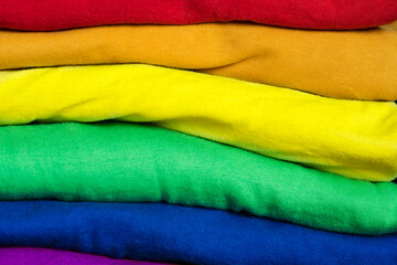 A stack of clothes folded in the colors of the LGBT community flag. Background with place for text for a template on the theme of tolerance and gender diversity