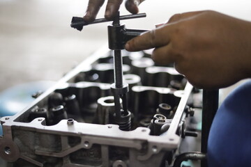 the hand of a mechanic is installing the valve seal of an overhauled car engine - obrazy, fototapety, plakaty