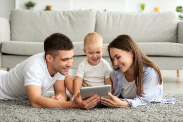 Cheerful Young Parents And Toddler Baby Relaxing With Digital Tablet At Home