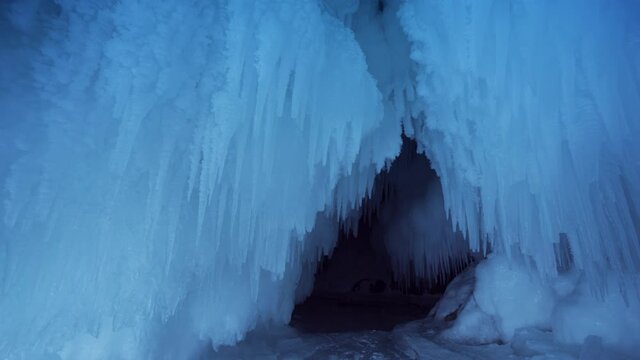 Many sharp icicles winter frozen grotto cave tunnel, arctic natural landscape. Permafrost Antarctica glaciers. Incredible splashes lake Baikal Russia. Glittering ice. Wild mysterious scenery. Dolly