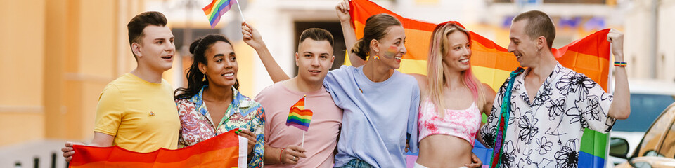 Multiracial men and women walking with rainbow flags during prid