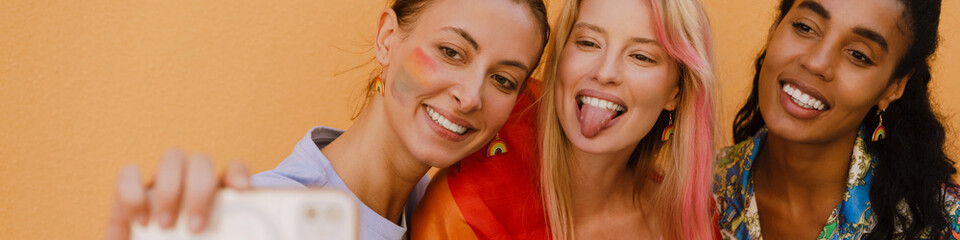 Multiracial women with rainbow flag taking selfie photo on cellp