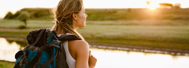 White blonde woman hiking with backpack on summer day