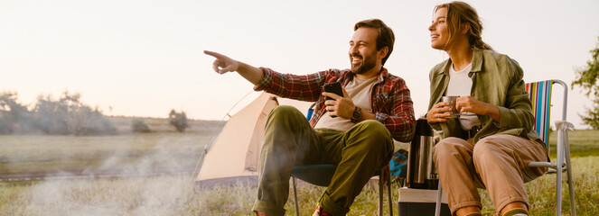 White couple smiling and drinking tea during camping together