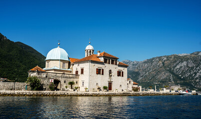 Fototapeta na wymiar Saint George island in Montenegro, closeup view from Kotor bay in sunny day. Ancient Mediterranean architecture surrounded with mountains in Adriatic sea