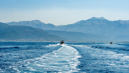 Obraz premium Foam trace in Adriatic sea after boat in Montenegro. Beautiful bay view with mountains landscapes
