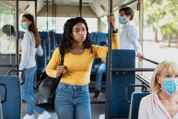 Focused black woman without mask standing in bus