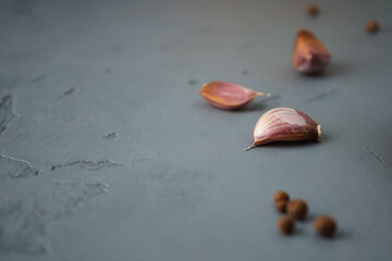 Garlic cloves and black pepper peas on a concrete surface