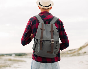 Male hipster traveler with backpack in hat looking forward to amazing mountains and valleys view