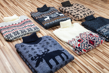 Collection of knitted Ugly turtleneck sweaters folded on wooden background
