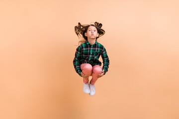 Photo of pretty funky school girl dressed checkered clothes jumping high diving bloated cheeks...