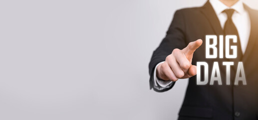 Businessman in a suit on a dark background holds the inscription BIG DATA. Storage Network Online Server Concept.Social network or business analytics representation