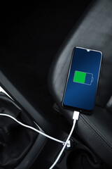 Mobile phone ,smartphone, cellphone is charged ,charge battery with usb charger in the inside of car. modern black car interior