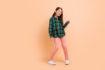 Fototapeta na wymiar Photo of charming funky schoolgirl wear plaid outfit dancing smiling isolated beige color background