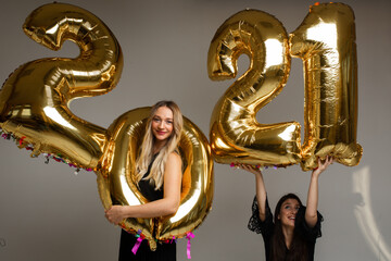 two beautiful girls in black dresses poses for the camera with big baloons 2021 and have a lot of fun