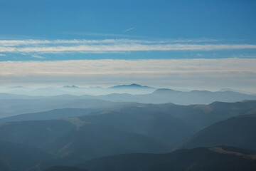 Fototapeta premium The beautiful landscape, silhouette of mountains covered with coniferous wood, cloudy blue sky after sunset