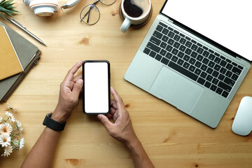 Man hands holding mock up smart phone with blank screen. Above view..