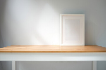 Empty picture frame on wooden table in bright living room.
