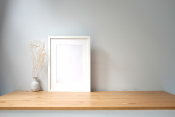 White empty picture frame and potted plant on wooden table.
