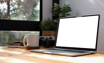 Home office desk with computer laptop, coffee cup and houseplant on wood table..