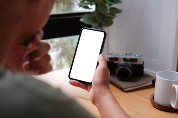 Close up view young man holding smart phone with white screen..