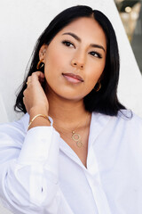 Hispanic young girl in white shirt posing with gold jewelry. Rings, earrings and pendants. fashion,...