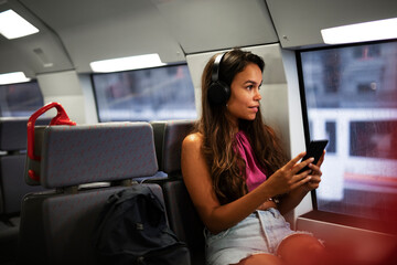 Young woman travelling by train. Beautiful girl listening the music while travel..