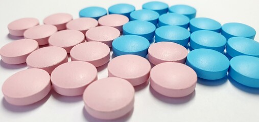 Pink and blue pills on a white background. Tablets for treatment without packaging. Useful vitamins for immunity.