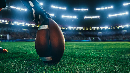 Fototapeta American Football Kickoff Game Start. Close-up Shot of an American Ball Standing on a Stadium Field Held by Professional Player. Preparation for Championship Game. obraz