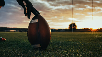 Fototapeta American Football Kickoff Game Start. Close-up Shot of an American Ball Standing on a Grass Field Held by Professional Player. Preparation for Championship Game. obraz