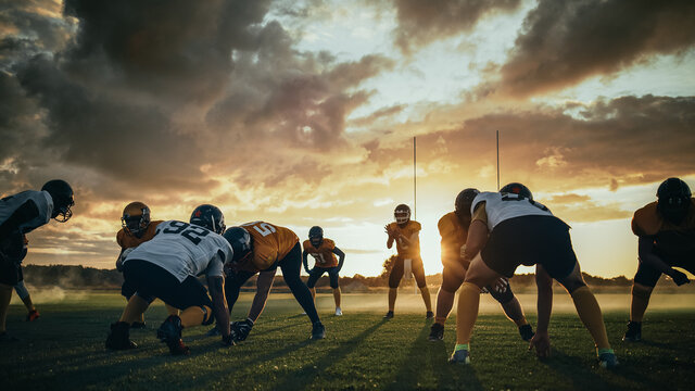 American Football Field Two Teams Compete: Players Pass and Run Attacking to Score Touchdown Points. Professional Athletes Fight for the Ball, Tackle. Dramatic Golden Hour Shot - Powered by Adobe