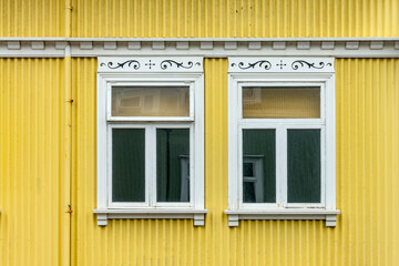 Windows on a yellow painted wall, colorful house, architecture detail in Reykjavik, Iceland