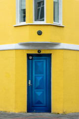 Fototapeta premium Blue door on a yellow painted colorful house, architecture detail in Reykjavik, Iceland