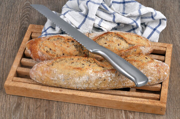 Baguettes de pain françaises dont une coupée sur une planche à pain avec un couteau à pain et...
