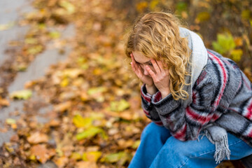 Depressed young woman sitting on bench in a public park
