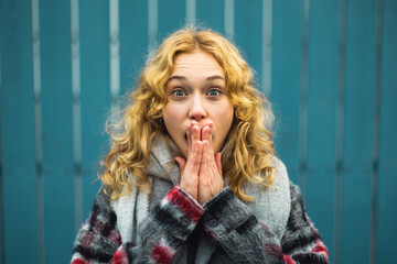 Amazed Young Woman With Mouth Open Against Blue Fence
