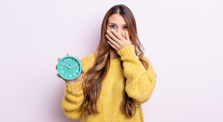 asiatic pretty woman covering mouth with hands with a shocked. alarm clock concept