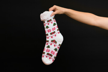 hand holding christmas socks on black background