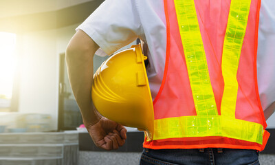 Closeup hand holding hard hat at home construction background