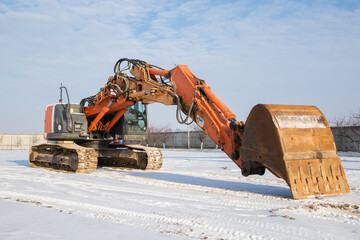 large orange powerful crawler excavator pulling the boom with a bucket forward at a construction...