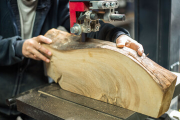 A man at work is sawing a tree. Machine for sawing wood, chipboard and cardboard. Manufacture of furniture, musical instruments and ruminants.