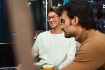 Man sitting at the cafeteria and chatting with their colleague while working