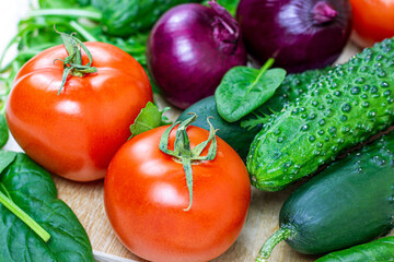 Fresh farm summer vegetables for salad: cucumbers, tomatoes, onions, peppers, arugula leaves in the kitchen on light background.