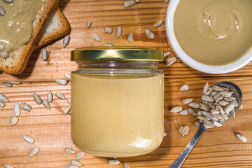 Sunflower seeds butter in small bow, jar and spoon. Modern alternative nut paste