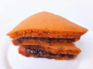 Kue Terang Bulan from Semarang, Indonesia. Popular street food, similar to pancake, with various filling (chocolate, strawberry jam, or refined sugar). On a white plate, isolated on white background